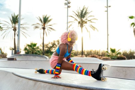 Téléchargez les photos : Belle femme patinant avec des patins à roulettes et s'amusant. Formation professionnelle de patineur et danseur le matin en portant des vêtements colorés et à la mode. - en image libre de droit