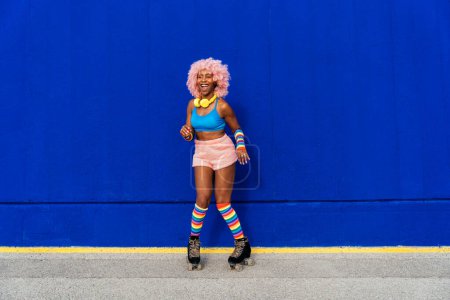 Photo for Beautiful woman skating with roller skates and having fun. Professional skater and dancer training in the morning wearing colored and fashionable clothes. - Royalty Free Image