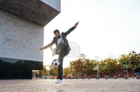 Téléchargez les photos : Image d'un homme d'affaires et joueur de soccer freestyle faisant des tours avec le ballon dans la rue. Concept sur le sport et les hommes d'affaires - en image libre de droit