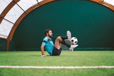 Photo for Cinematic image of a soccer freestyle player making tricks with the ball on a artificial grass court indoor. Concept about sport and people lifestyle - Royalty Free Image