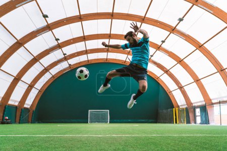Photo for Cinematic image of a soccer freestyle player making tricks with the ball on a artificial grass court indoor. Concept about sport and people lifestyle - Royalty Free Image