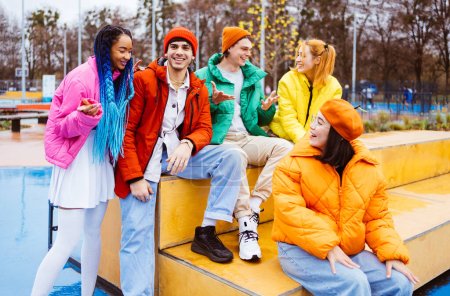 Photo for Multiracial group of young happy friends meeting outdoors in winter, wearing winter jackets and having fun - Multiethnic millennials bonding in a urban area, concepts about youth and social releationships - Royalty Free Image