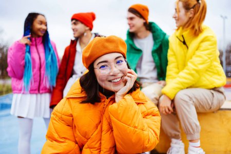 Multiracial group of young happy friends meeting outdoors in winter, wearing winter jackets and having fun, asian woman portrait - Multiethnic millennials bonding in a urban area, concepts about youth and social releationships