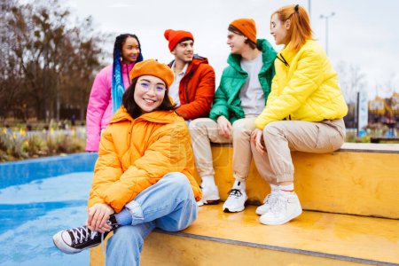 Foto de Grupo multirracial de jóvenes amigos felices que se reúnen al aire libre en invierno, vistiendo chaquetas de invierno y divirtiéndose, retrato de mujer asiática: los millennials multiétnicos que se unen en un área urbana, conceptos sobre la juventud y las liberaciones sociales - Imagen libre de derechos