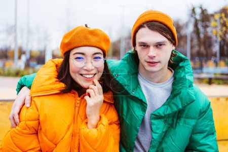Photo for Multiracial young couple of lovers dating outdoors in winter, wearing winter jackets and having fun - Multiethnic millennials bonding in a urban area, concepts about youth and social releationships - Royalty Free Image