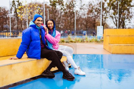 Photo for Multiracial young couple of lovers dating outdoors in winter, wearing winter jackets and having fun - Multiethnic millennials bonding in a urban area, concepts about youth and social releationships - Royalty Free Image