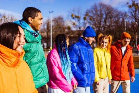 Foto de Grupo multiétnico de jóvenes amigos felices que se reúnen al aire libre en invierno, usan chaquetas de invierno y se divierten: millennials multiétnicos que se unen en un área urbana, conceptos sobre la juventud y las liberaciones sociales - Imagen libre de derechos