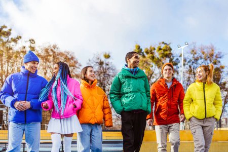 Foto de Grupo multiétnico de jóvenes amigos felices que se reúnen al aire libre en invierno, usan chaquetas de invierno y se divierten: millennials multiétnicos que se unen en un área urbana, conceptos sobre la juventud y las liberaciones sociales - Imagen libre de derechos