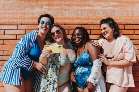 Foto de Group of beautiful plus size women with swimwear bonding and having fun at the beach, posing on a brick wall background - Curvy female friends enjoying summertime at the sea, concepts about body acceptance, body positive and self confidence - Imagen libre de derechos