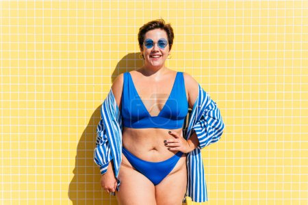 Photo for Beautiful and confident plus size woman having fun at the beach, posing on colorful wall background -  concepts about body acceptance, body positive, self confidence and body care - Royalty Free Image