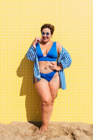 Foto de Beautiful and confident plus size woman having fun at the beach, posing on colorful wall background -  concepts about body acceptance, body positive, self confidence and body care - Imagen libre de derechos
