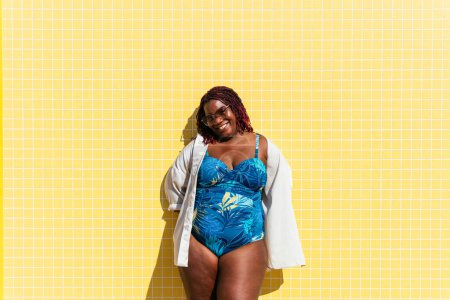 Foto de Beautiful and confident plus size woman having fun at the beach, posing on colorful wall background -  concepts about body acceptance, body positive, self confidence and body care - Imagen libre de derechos