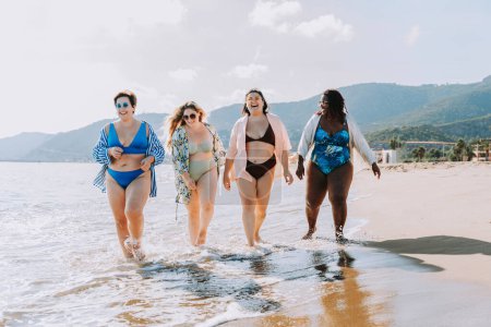 Photo for Group of beautiful plus size women with swimwear bonding and having fun at the beach - Group of curvy female friends enjoying summertime at the sea, concepts about body acceptance, body positive and self confidence - Royalty Free Image