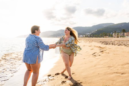 Photo for Two beautiful plus size women with swimwear bonding and having fun at the beach - Curvy female friends enjoying summertime at the sea, concepts about body acceptance, body positive and self confidence - Royalty Free Image