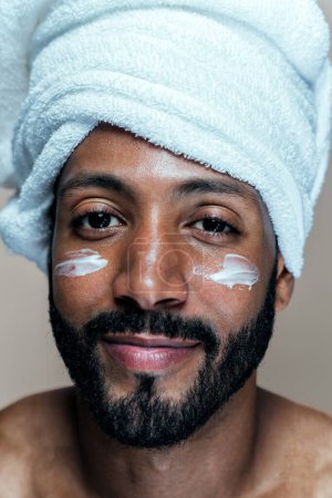 Téléchargez les photos : Image d'un jeune homme prenant soin de sa peau. Studio beauté tourné sur les soins de la peau et les produits pour l'hygiène personnelle. - en image libre de droit