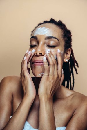 Schöne Frau macht Haut- und Gesichtsbehandlungen. Studioaufnahme mit Fokus auf Kosmetik- und Hautpflegekonzepte