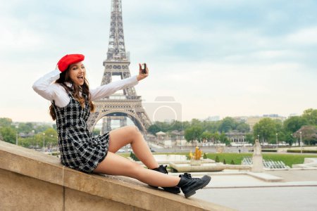 Photo for Beautiful young woman visiting paris and the eiffel tower. Parisian girl with red hat and fashionable clothes having fun in the city center and landmarks area - Royalty Free Image