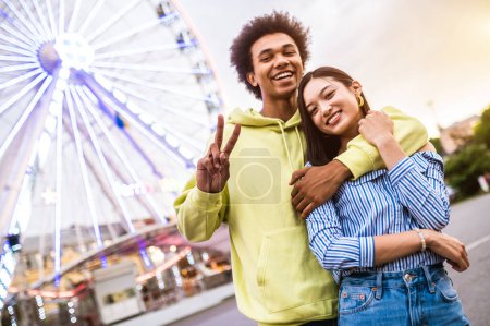Téléchargez les photos : Multiracial young couple of lovers dating at theferry wheel in the amusement park - People with mixed races having fun outdoors in the city- Friendship, releationship and lifestyle concepts - en image libre de droit