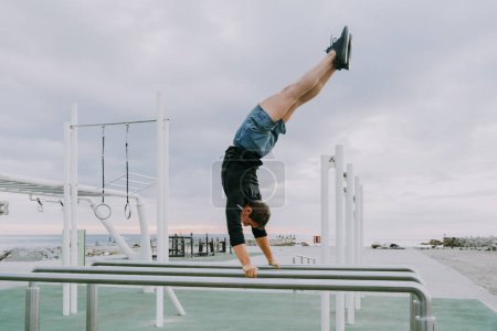 Téléchargez les photos : Sportive and athletic man doing functional training exercise at the outdoor gym - Adult athlete doing workout at sunrise at calisthenics park on the beach - Fitness, healthy lifestyle and sport concepts - en image libre de droit