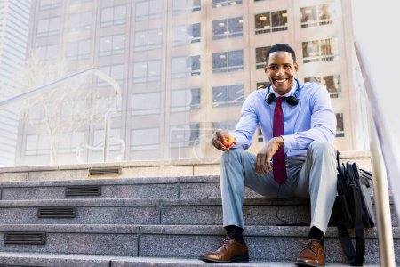 Téléchargez les photos : Charmant homme d'affaires afro-américain PDG dans un élégant costume élégant d'entreprise dans un centre d'affaires en plein air noir banlieusard aller au travail, ville et quartier financier en arrière-plan - en image libre de droit
