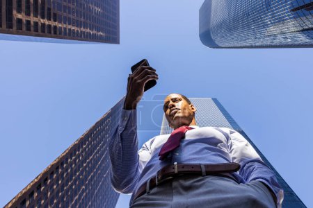 Téléchargez les photos : Handsome male african american business man CEO in a stylish corporate elegant suit in a business center outdoors - Black male commuter going to work, city and financial district in the background - en image libre de droit