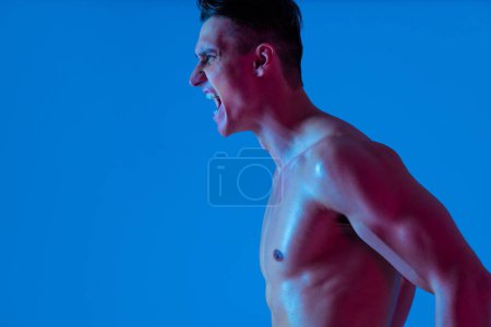 Photo for Athletic man with fit muscular body training in studio - Active man doing a workout, colorful lighting and background, concepts about fitness, sport and health lifestyle - Royalty Free Image