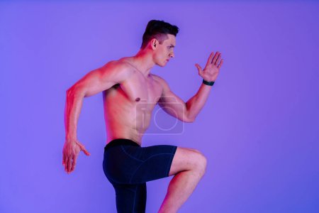 Foto de Hombre atlético con entrenamiento corporal muscular en forma en el estudio - Hombre activo haciendo un entrenamiento, iluminación colorida y fondo, conceptos sobre fitness, deporte y estilo de vida saludable - Imagen libre de derechos