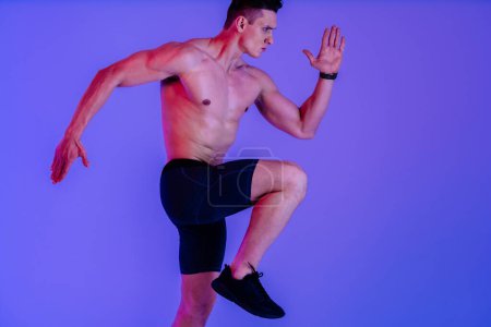 Téléchargez les photos : Homme athlétique avec entraînement musculaire en studio - Homme actif faisant une séance d'entraînement, éclairage coloré et arrière-plan, concepts de fitness, sport et mode de vie sain - en image libre de droit