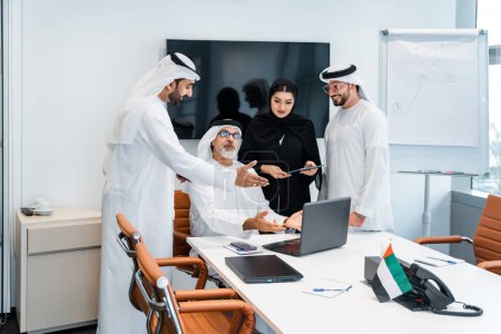 Foto de Grupo de empresarios de Oriente Medio que usan ropa emirati tradicional en la oficina de Dubái - Equipo de trabajo y lluvia de ideas en los Emiratos Árabes Unidos - Imagen libre de derechos