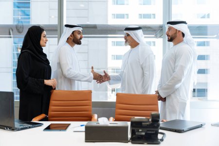 Téléchargez les photos : Groupe de gens d'affaires du Moyen-Orient portant des vêtements traditionnels emirati au bureau de Dubaï - Équipe d'affaires travaillant et réfléchissant aux EAU - en image libre de droit