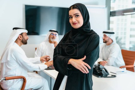 Photo for Group of middle-eastern corporate business people wearing traditional emirati clothes meeting in the office in Dubai - Business team working and brainstorming in the UAE - Royalty Free Image