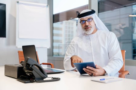 Foto de Retrato del hombre de negocios corporativo maduro de Oriente Medio usando kadora y trabajando en la oficina en Dubai - Imagen libre de derechos