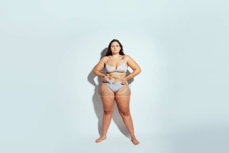 Téléchargez les photos : Femme de taille plus posant en studio en lingerie. Modèle sur fond blanc. Studio lumière dure tourné - en image libre de droit