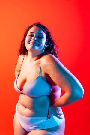 Foto de Mujer de talla grande posando en estudio en lencería. Modelo sobre fondo de color. Tiro de estudio de luz dura - Imagen libre de derechos