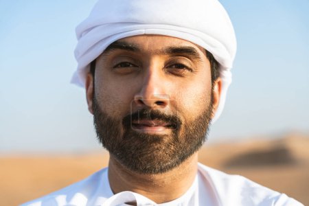 Photo for Handsome and successful middle-eastern man wearing traditional emirati arab kandura in the desert - Arabian muslim adult person at the sand dunes in Dubai - Royalty Free Image