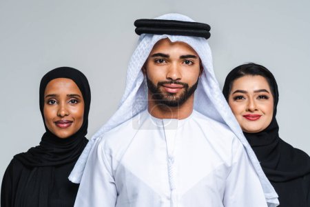 Téléchargez les photos : Magnifiques femmes arabes du Moyen-Orient avec une robe traditionnelle abaya et un homme du Moyen-Orient portant une kandora en studio - Groupe d'adultes arabes musulmans portrait à Dubaï, Émirats arabes unis - en image libre de droit