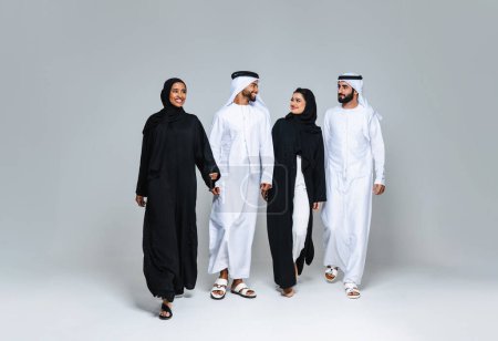 Photo for Beautiful arab middle-eastern women with traditional abaya dress and middle easter man wearing kandora in studio - Group of arabic muslim adults portrait in Dubai, United Arab Emirates - Royalty Free Image