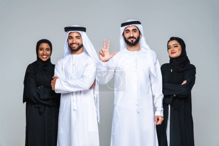 Foto de Hermosas mujeres árabes de Oriente Medio con vestido tradicional abaya y hombre de Pascua medio usando kandora en el estudio - Grupo de árabes musulmanes adultos retrato en Dubai, Emiratos Árabes Unidos - Imagen libre de derechos