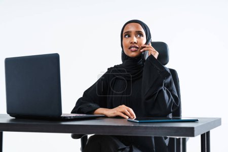 Foto de Hermosa mujer de negocios corporativa árabe de Oriente Medio con vestido tradicional abaya que trabaja en la oficina- retrato femenino musulmán árabe adulto en el escritorio de la computadora en Dubai, Emiratos Árabes Unidos - Imagen libre de derechos