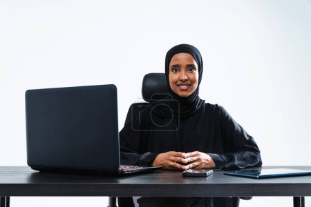 Photo for Beautiful arab middle-eastern corporate businesswoman with traditional abaya dress working in the office- Arabic muslim adult female portrait at computer desk in Dubai, United Arab Emirates - Royalty Free Image