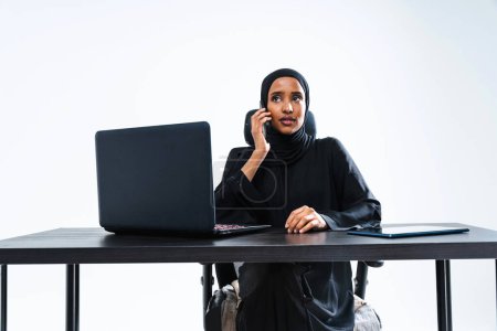 Téléchargez les photos : Belle femme d'affaires arabe du Moyen-Orient avec robe abaya traditionnelle travaillant dans le bureau Portrait féminin arabe musulman adulte au bureau informatique à Dubaï, Émirats arabes unis - en image libre de droit