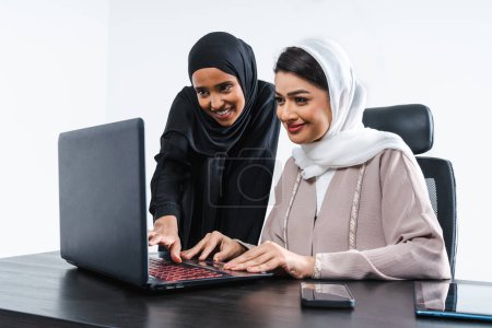 Foto de Hermosas mujeres árabes de Oriente Medio con vestido tradicional abaya en el estudio - mujeres musulmanas árabes adultas empresarias que trabajan juntas en la oficina en Dubai, Emiratos Árabes Unidos - Imagen libre de derechos