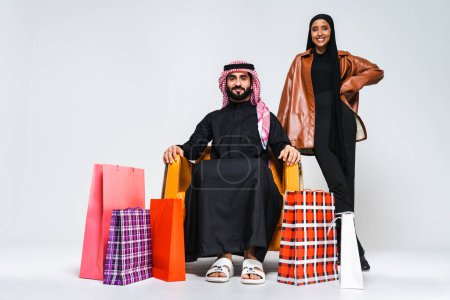 Photo for Beautiful saudi arabian middle-eastern happy couple of lovers wearing traditional abaya and thwab in studio - Arabic muslim adult people bonding and shopping at mall - Royalty Free Image