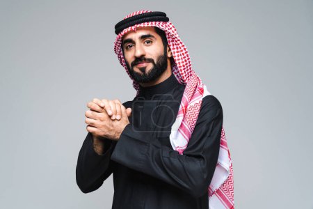 Foto de Hombre guapo árabe de Oriente Medio con ropa tradicional saudí en el estudio - Hombre árabe musulmán adulto hombre de negocios con retrato thwab aislado sobre fondo gris - Imagen libre de derechos