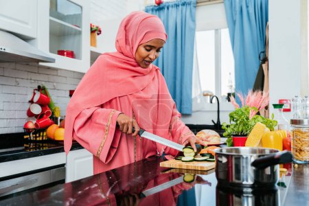 Foto de Mujer feliz de Oriente Medio vistiendo abaya en casa - Hermoso retrato musulmán adulto femenino en el apartamento, conceptos sobre la vida doméstica y el estilo de vida islámico - Imagen libre de derechos