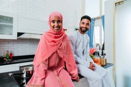 Photo for Happy middle-eastern couple wearing traditional arab clothing at home - Married arabian husband and wife bonding together in the apartment, concepts about relationship, domestic life and emirati lifestyle - Royalty Free Image