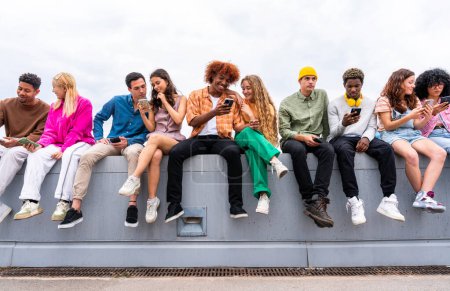 Téléchargez les photos : Heureux groupe multiethnique ludique de jeunes amis qui se lient en plein air étudiants multiraciaux milléniaux se réunissant dans la ville, concepts de la jeunesse, mode de vie des gens, la diversité, l'adolescence et la vie urbaine - en image libre de droit