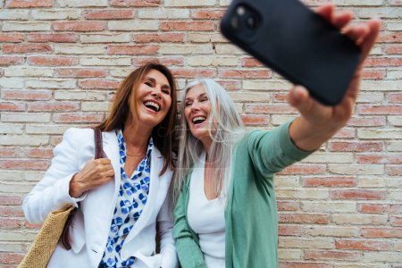 Foto de Hermosas mujeres mayores vinculación al aire libre en la ciudad Atractivas alegres amigas maduras divertirse, compras y vinculación, conceptos sobre el estilo de vida de los ancianos - Imagen libre de derechos