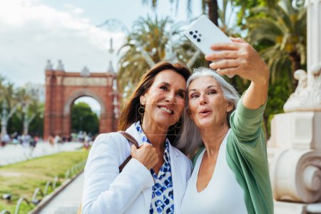 Téléchargez les photos : Belles femmes âgées coller en plein air dans la ville - Attrayant joyeux amis femmes mûres qui s'amusent, faire du shopping et coller, concepts sur le mode de vie des personnes âgées - en image libre de droit