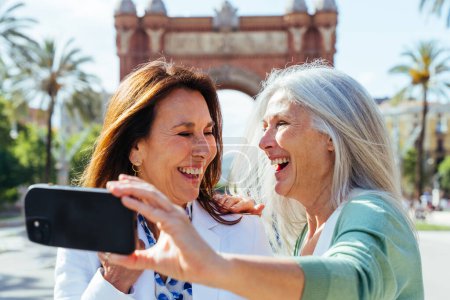 Téléchargez les photos : Belles femmes âgées coller en plein air dans la ville - Attrayant joyeux amis femmes mûres qui s'amusent, faire du shopping et coller, concepts sur le mode de vie des personnes âgées - en image libre de droit